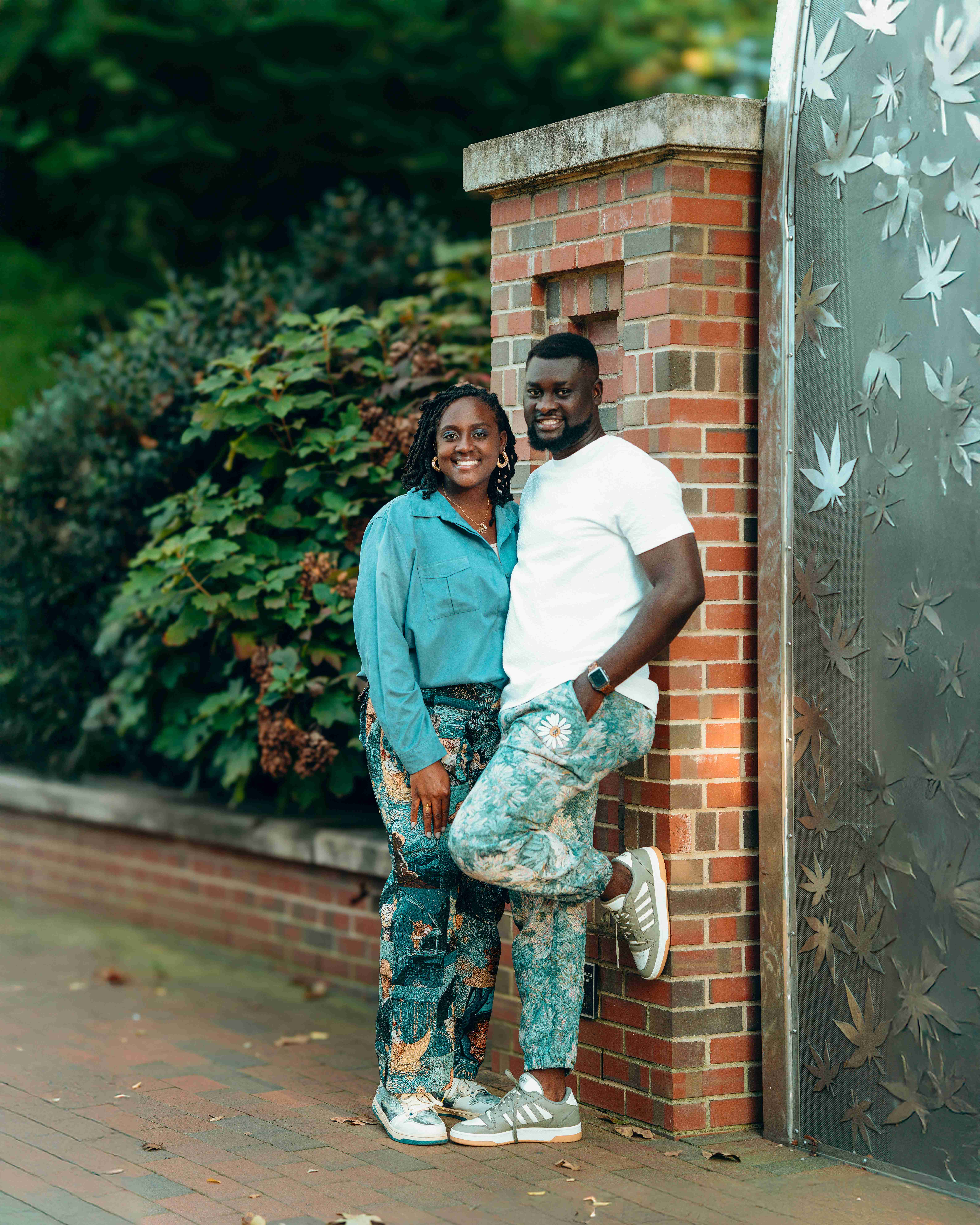 Couple posing against brick wall structure